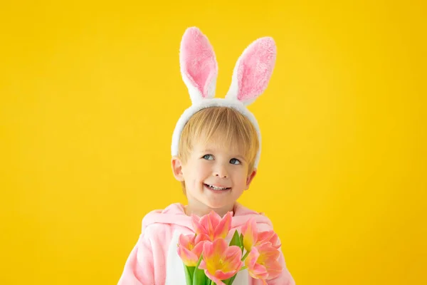 Lustiges Kind trägt Osterhasen vor gelbem Hintergrund — Stockfoto