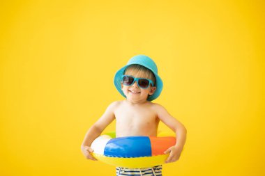 Sarı arka planda lastik yüzük tutan mutlu çocuk portresi. Çocuk yaz tatilinde eğleniyor. Rüya ve hayal gücü kavramı