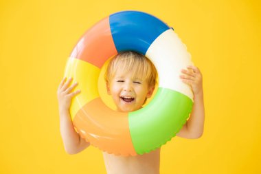 Sarı arka planda lastik yüzük tutan mutlu çocuk portresi. Çocuk yaz tatilinde eğleniyor. Rüya ve hayal gücü kavramı