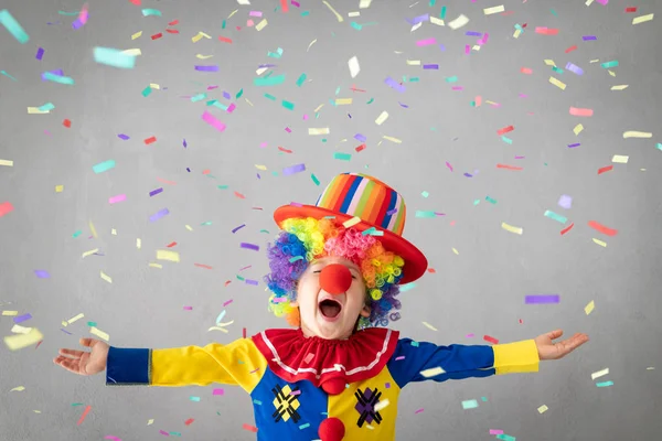 Funny kid clown against falling confetti. Happy child playing at home. 1 April Fool\'s day concept
