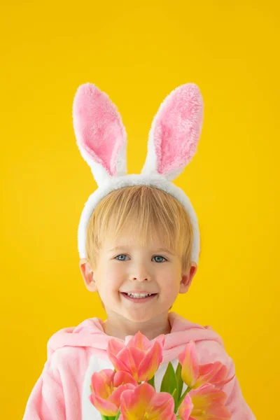 穿着黄色背景的复活节兔子的有趣的孩子 快乐的孩子拿着一束鲜花 春假概念 — 图库照片