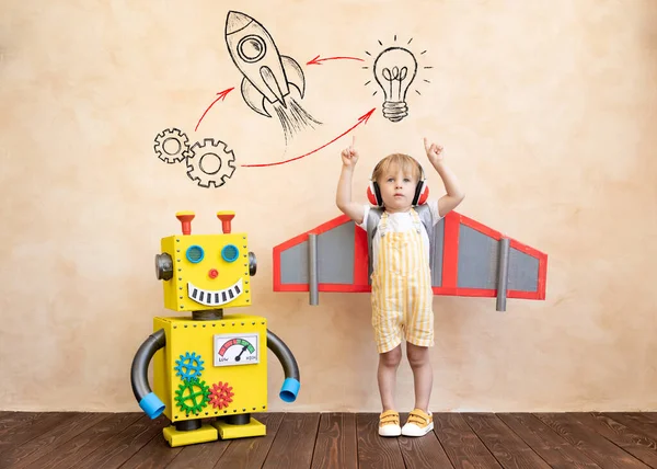 段ボールの翼を持つ幸せな子供 おもちゃの手作りロボットで遊ぶ面白い子供 創造的かつ革新的な技術コンセプト — ストック写真