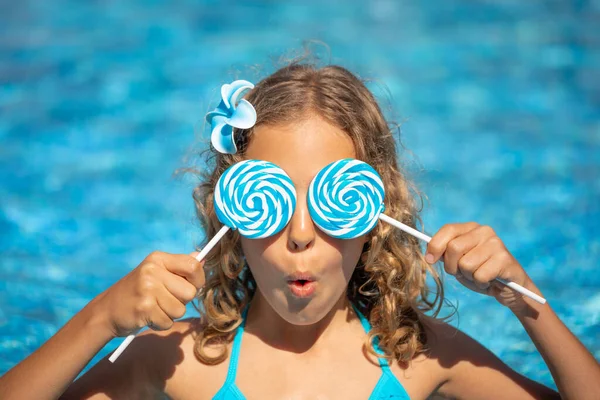 在游泳池里玩棒棒糖的孩子很惊讶 在蓝水背景下度过暑假的女孩 — 图库照片