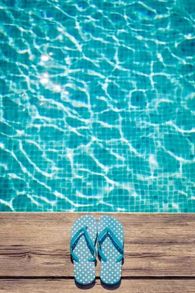 プールの近くの木製の背景にフリップフロップ 夏休みのコンセプト — ストック写真