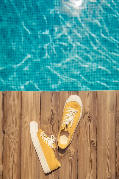 Gelbe Turnschuhe Auf Hölzernem Hintergrund Der Nähe Des Schwimmbades Sommerferienkonzept — Stockfoto