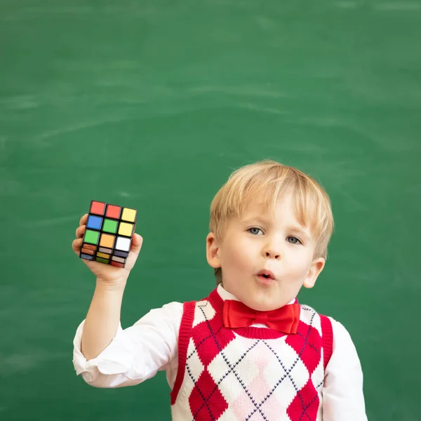 Dziecko Pokazując Rubik Cube Kombinacji Puzzle Przeciwko Zielonej Tablicy — Zdjęcie stockowe