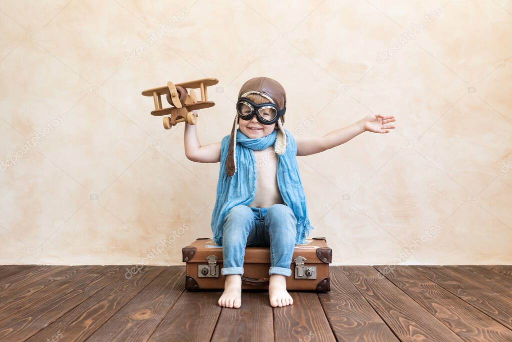 Happy child playing with vintage wooden airplane. Kid having fun at home. Imagination and freedom concept