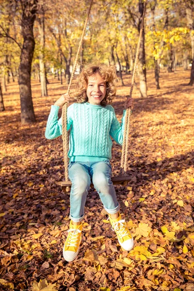 快乐的孩子在秋天的公园里玩得很开心 女孩在黄色模糊的叶子背景下荡秋千 自由和无忧无虑的概念 — 图库照片
