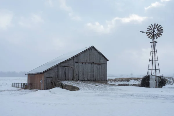 Старый амбар и ветряная мельница в заснеженном среднезападном ландшафте - рядом с Авиллой, Индиана, США. - Зимнее земледелие Стоковое Изображение