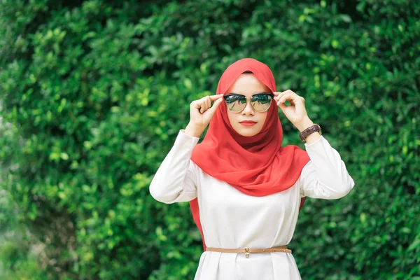 Retrato de la joven mujer musulmana feliz hiyab rojo sobre difuminado el fondo del campo verde . —  Fotos de Stock