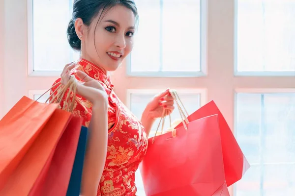 Felice donna cinese asiatica indossa un abito qipao tradizionale con borse della spesa godendo nello shopping in Capodanno cinese . — Foto Stock