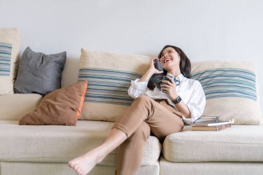 Genç Asyalı bayan çalışanın iş saatinde ev ofisinde müşteriyle telefon görüşmesi yapması. Ev kavramından çalışmak