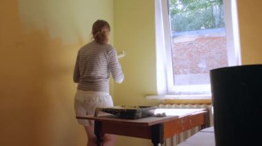 Genç Bayan duvara resim yapıyor.