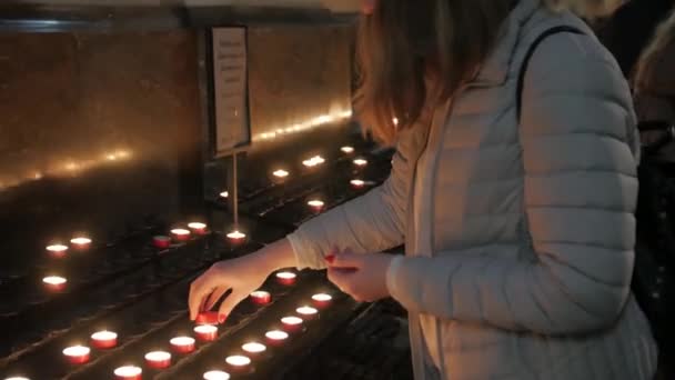 Chica enciende una vela en la iglesia — Vídeos de Stock