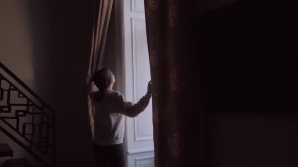 Menina abre cortinas olha para fora — Vídeo de Stock