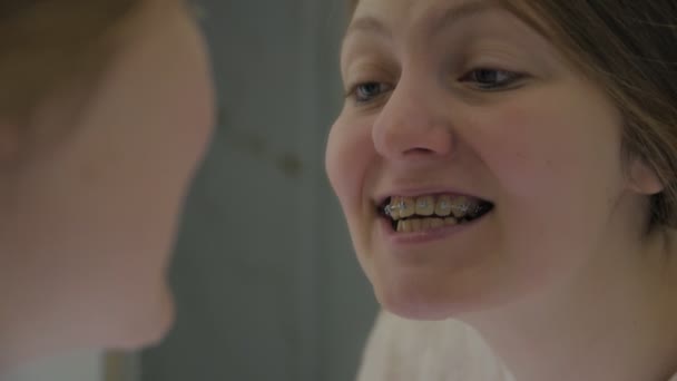 Dziewczyna z aparatem na zęby wygląda w lustrze — Wideo stockowe