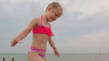 Küçük kız sahilde eğleniyor.
