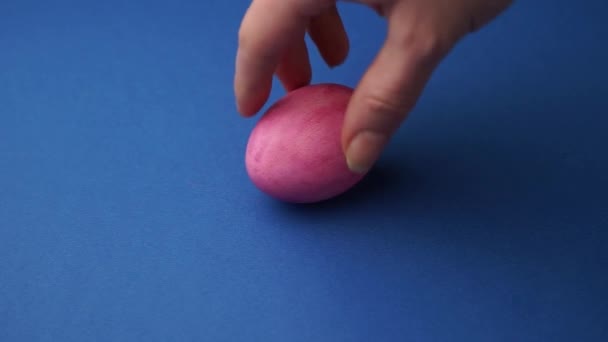 La mano de una mujer tuerce un huevo de gallina pintado — Vídeos de Stock