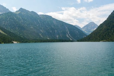 Seçici odak noktası, Almanya sınırında dağlı bir Alp mavi gölü.