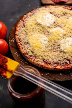 Domates ezmeli pizza, füme sosis, mozzarella peyniri ve üzerine parmesan peyniri serpiştirilmiş.