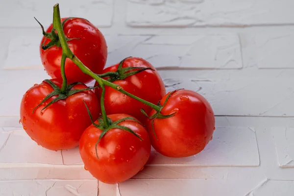 Röda Mogna Tomater Med Vattendroppar Grön Gren Ett Ljust Bord — Stockfoto