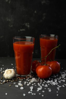 Kırmızı domatesli taze domates suyu ve koyu arkaplanda kaba tuz.