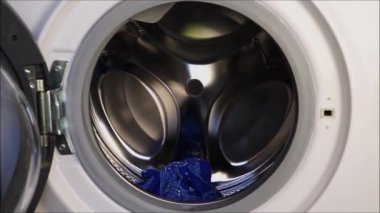  Yıkanmaya hazırlanıyorum. Bir kız beyaz çamaşır makinesine renkli şeyler yüklüyor.