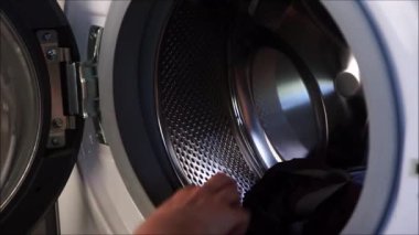 Yıkanmaya hazırlanıyorum. Bir kız beyaz çamaşır makinesine renkli şeyler yüklüyor.