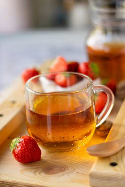 Çilekli sıcak siyah çay, ahşap tahtada.