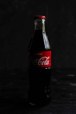 Cam şişe Coca-Cola karbonatlı içecek, üzerinde kırmızı etiket var.