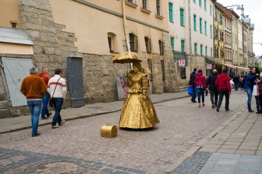 Lviv, Ukrayna - 1 Mayıs 2017: Lviv şehir merkezindeki ana kare şemsiye ile altın elbise giymiş Street sanatçılar