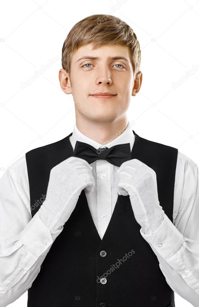 Portrait of young handsome waiter fixing his bow tie on a suit
