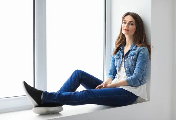 Woman relaxing on window sill — Stock Photo, Image