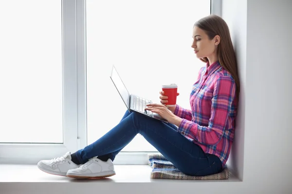 Vrouw op de vensterbank met laptop — Stockfoto