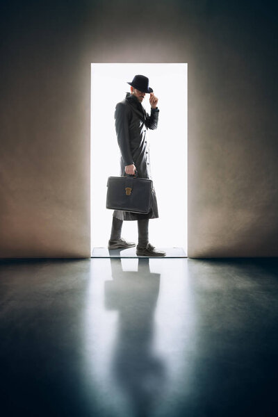 Man silhouette in hat and raincoat