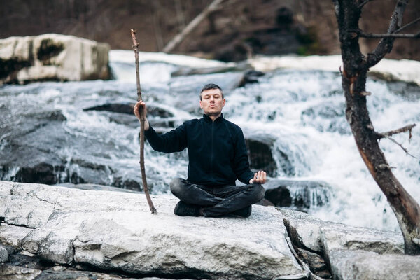 Man meditating on waterfall