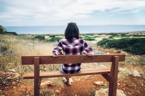 Jovem mulher sentada no banco de madeira — Fotografia de Stock