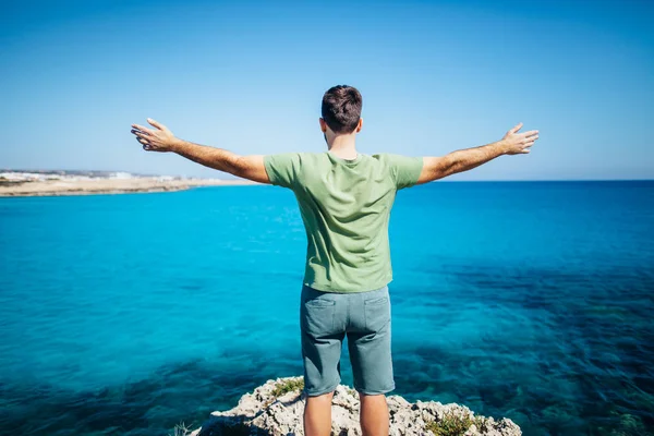 Young man with open arms on cliff — Stock Photo, Image