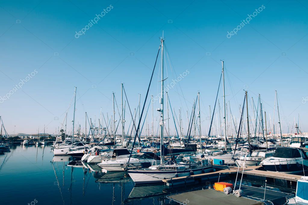 Sailboats and yachts in harbor under clear blue sky