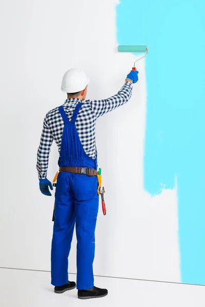 Pintor homem pintura parede em azul — Fotografia de Stock