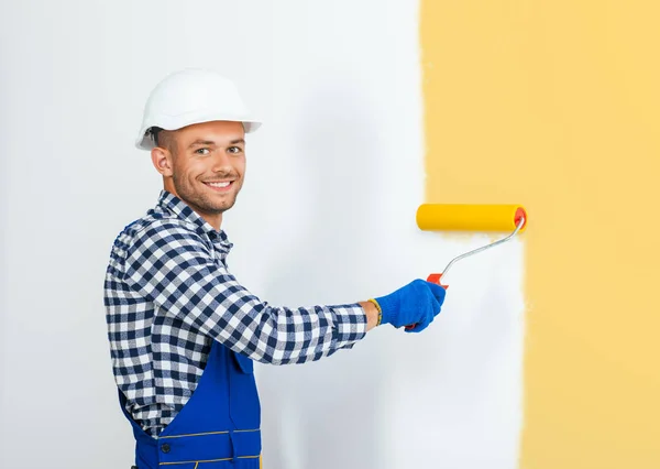 Peintre souriant mur de peinture en jaune — Photo