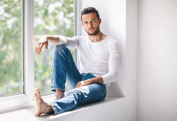 Thoughtful man relaxing on window sill — Stock Photo, Image