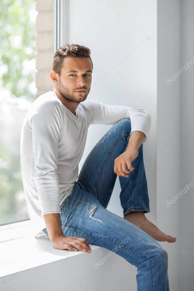 thoughtful man relaxing on window sill
