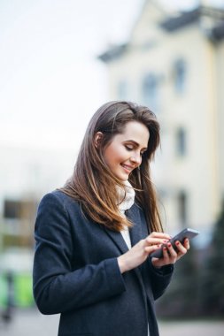 Mutlu kadın cep telefonu ile mesaj yazarken sokak şehir