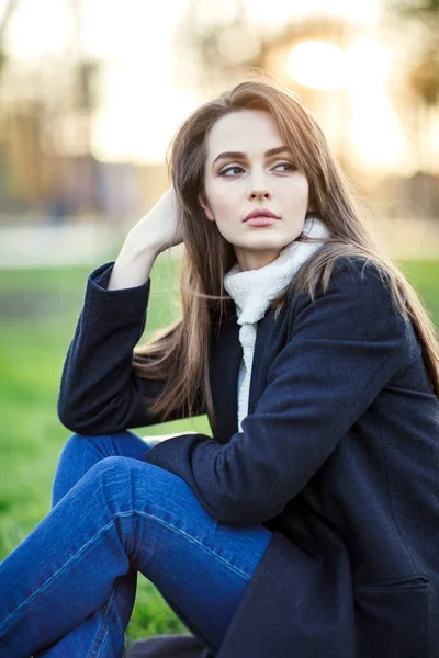 Young beautiful woman sitting on a grass in sun light on sunset — Stock Photo, Image