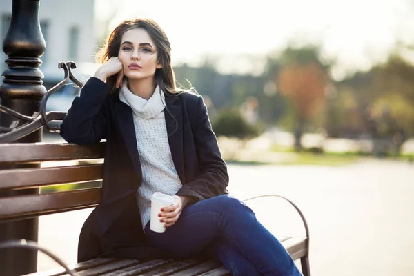 Donna con coppa seduta su una panchina — Foto Stock