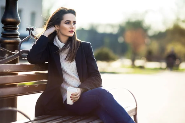 Frau mit Tasse sitzt auf einer Bank — Stockfoto