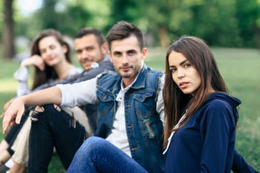 Yeşil çimenlerin üzerinde oturan genç insanlar