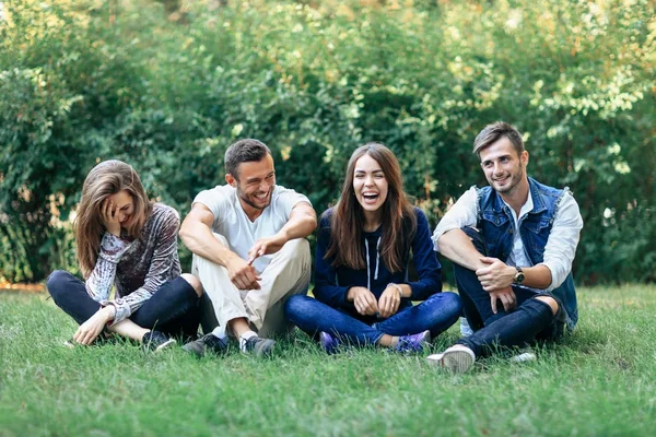 Смешные смеющиеся друзья сидят на траве — стоковое фото