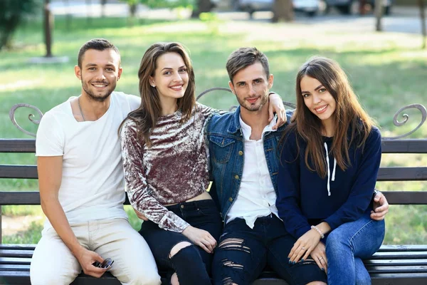 Jovens amigos sentados no banco ao ar livre — Fotografia de Stock